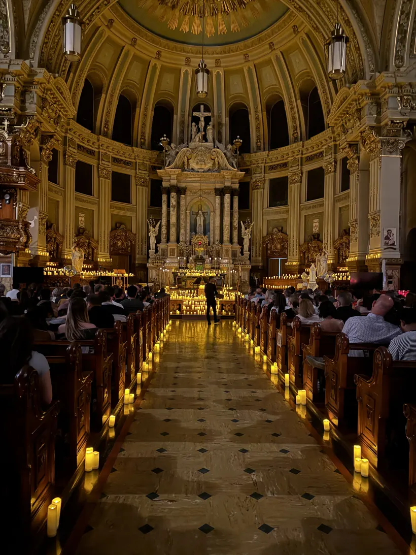 A candlelight concert inside an ornate church, aisles lined with glowing candles