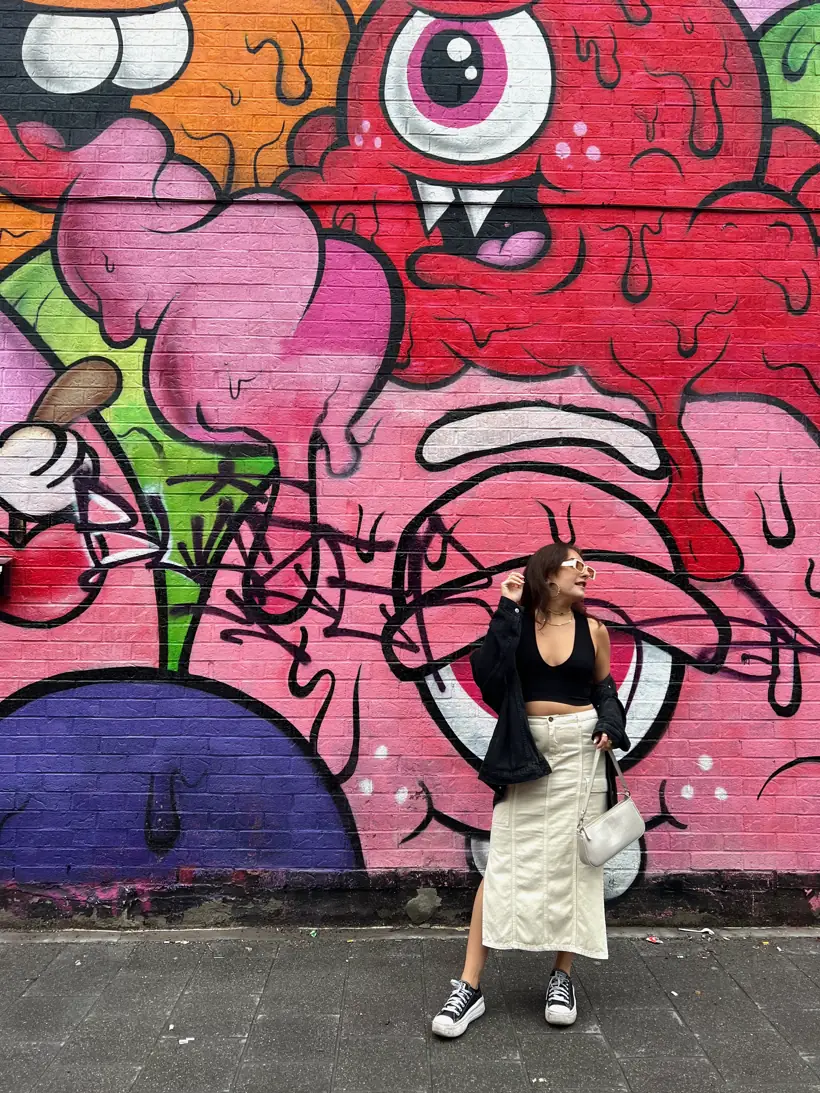 Bold pink mural on a Mile End street, a stylishly dressed passerby in front
